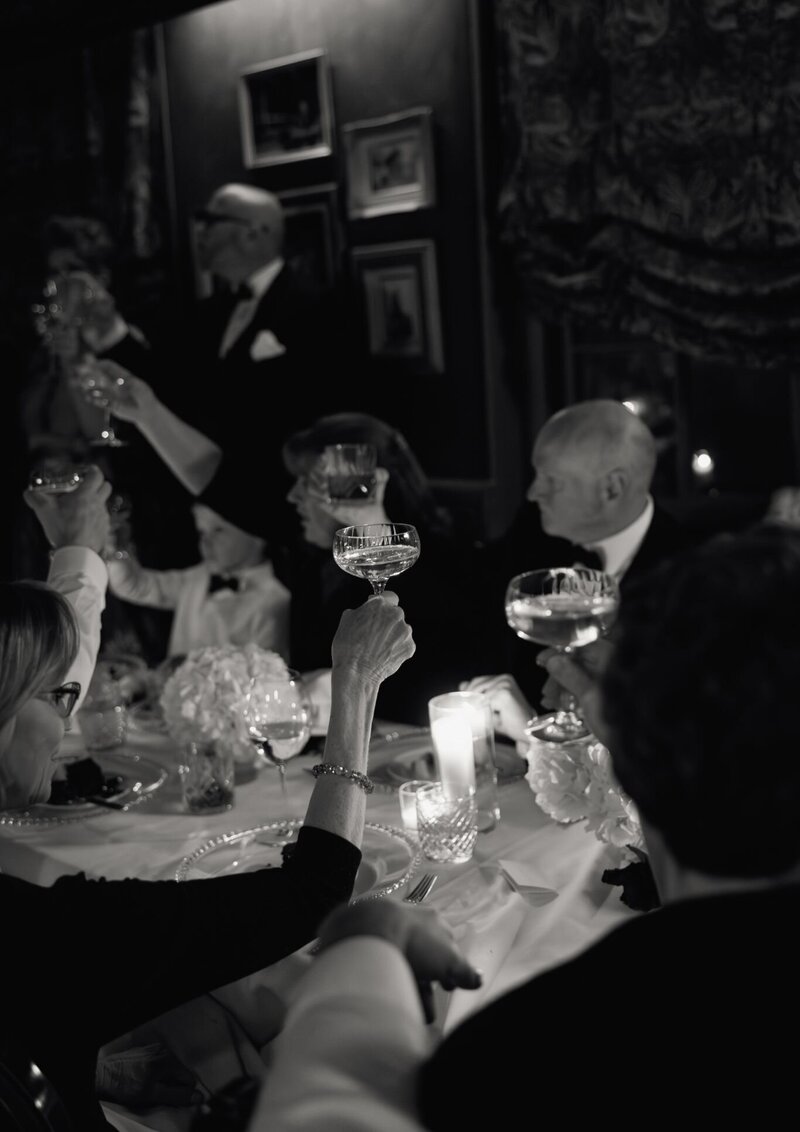 Bride and groom sharing a toast while sipping champagne from a stacked tower of coupe glasses during their wedding celebration.
