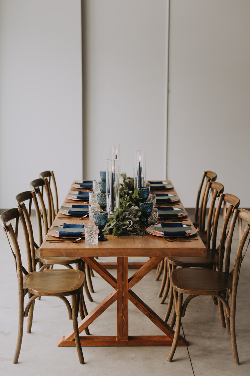 Elegant Canmore wedding reception table with custom printed menu card, navy linens, and luxury gold flatware.