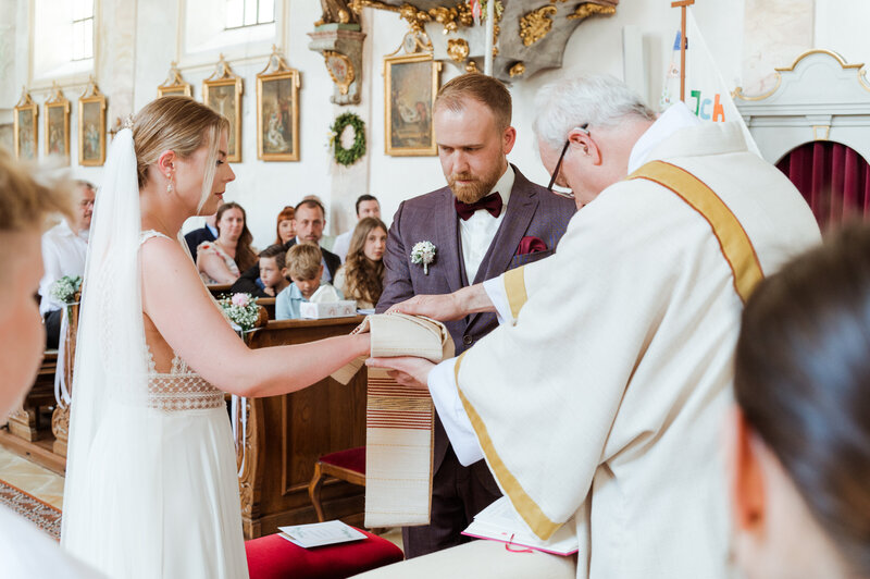 Brautpaar wird von Pfarrer in der Kirche gesegnet