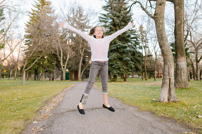 A girl jumping in the park while wearing prosthetics