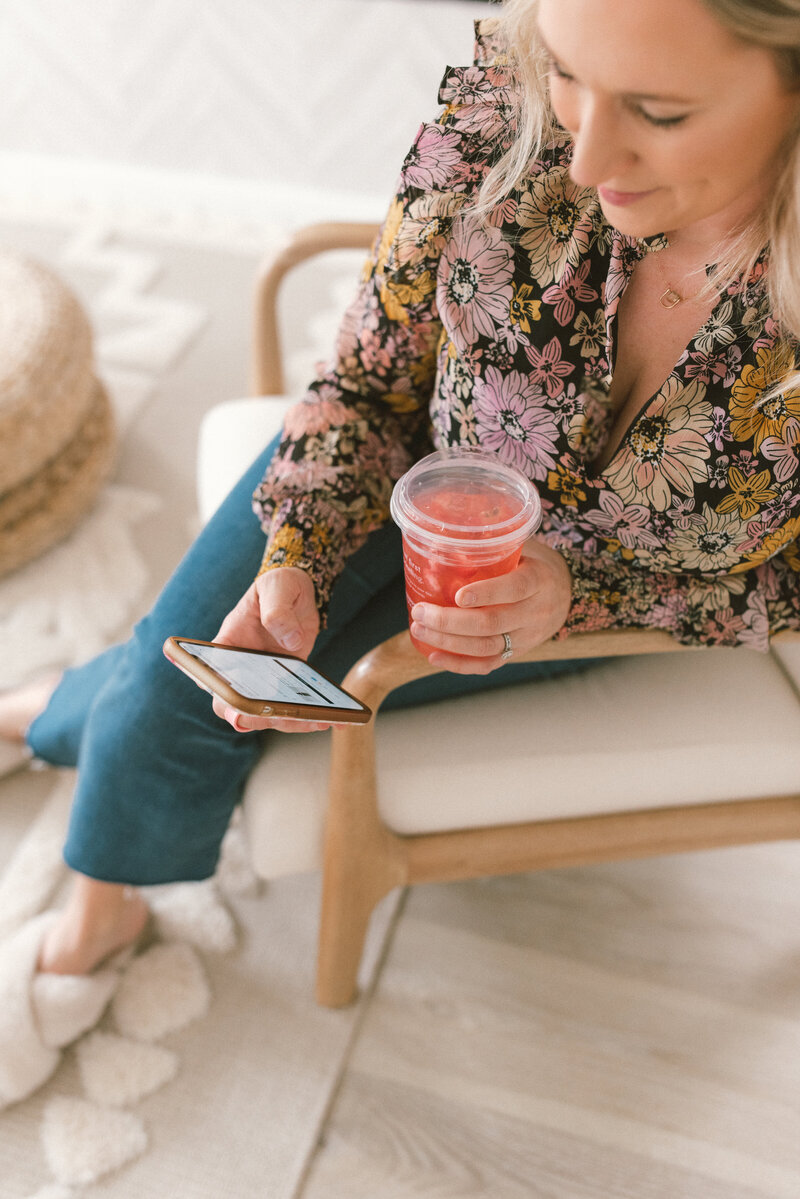 Sarah Kaetterhenry sitting down checking phone and drinking Starbucks Refresher