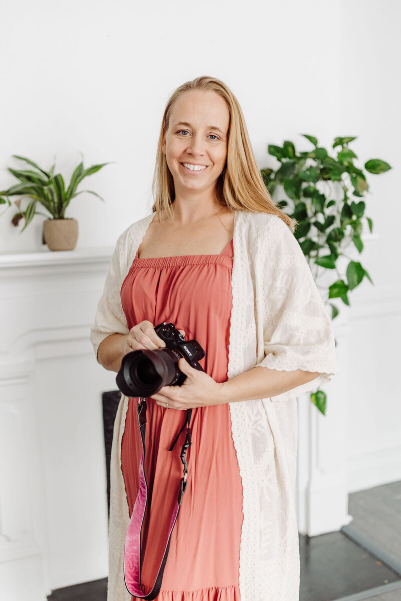 photographer standing beside a window with a white curtain