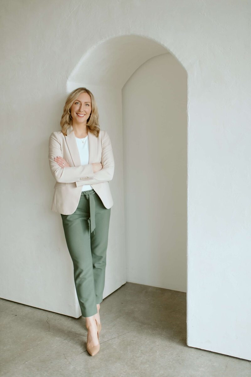 Orthopedic Physical therapy specialist Dr Gwen leans against a wall, smiling.