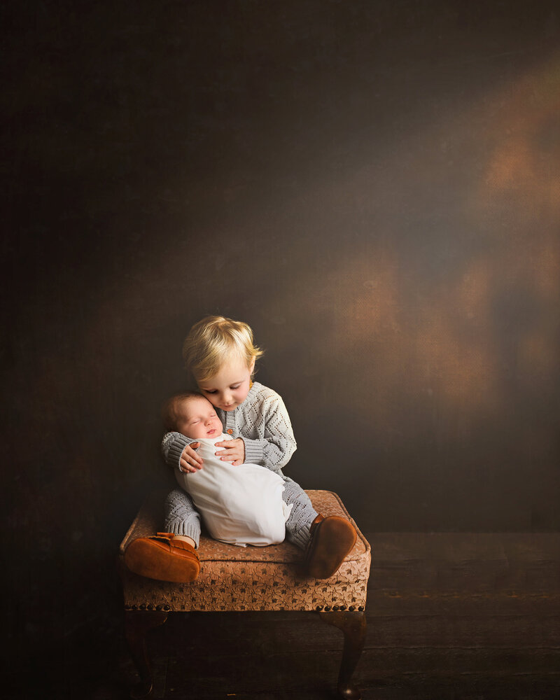 Newborn portrait of toddler holding sibling