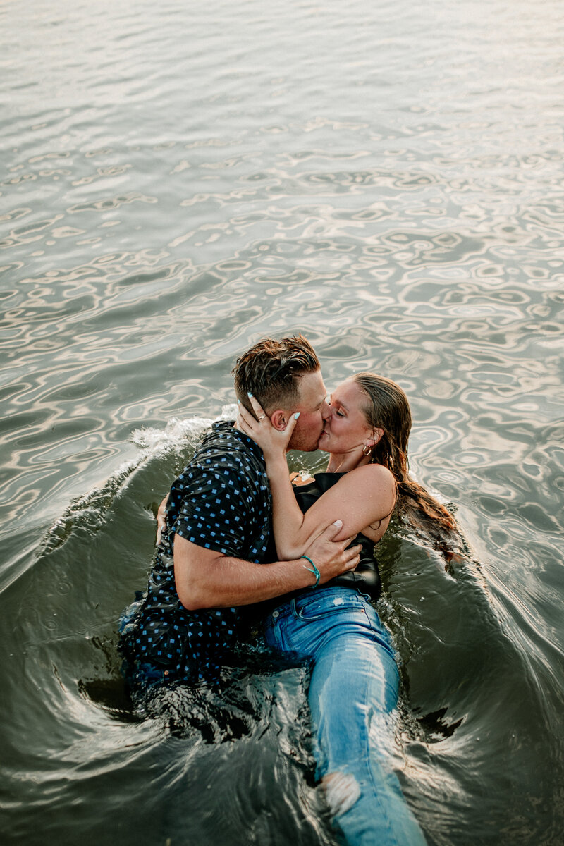 A carefree couple jump into the lake to cool off following their Minnesota summer couples session.