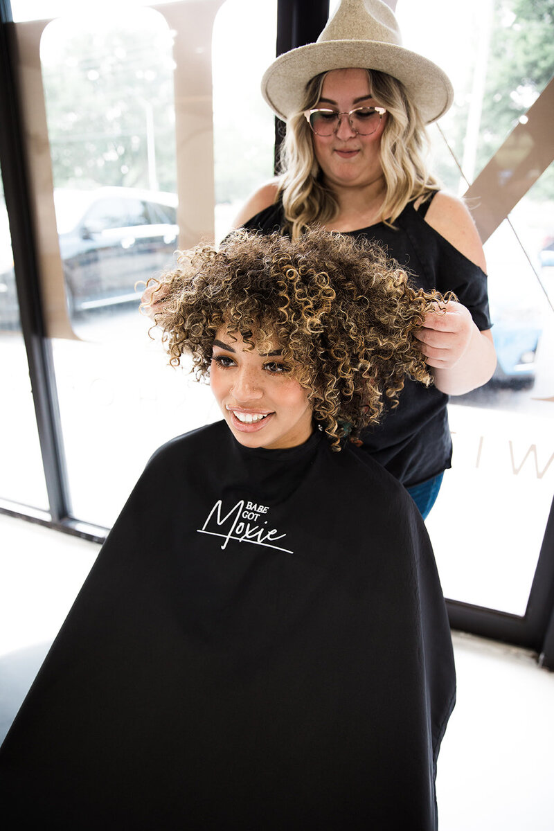 Kylie, owner and curly stylist at Moxie by KC, works with her client's big curly hairstyle