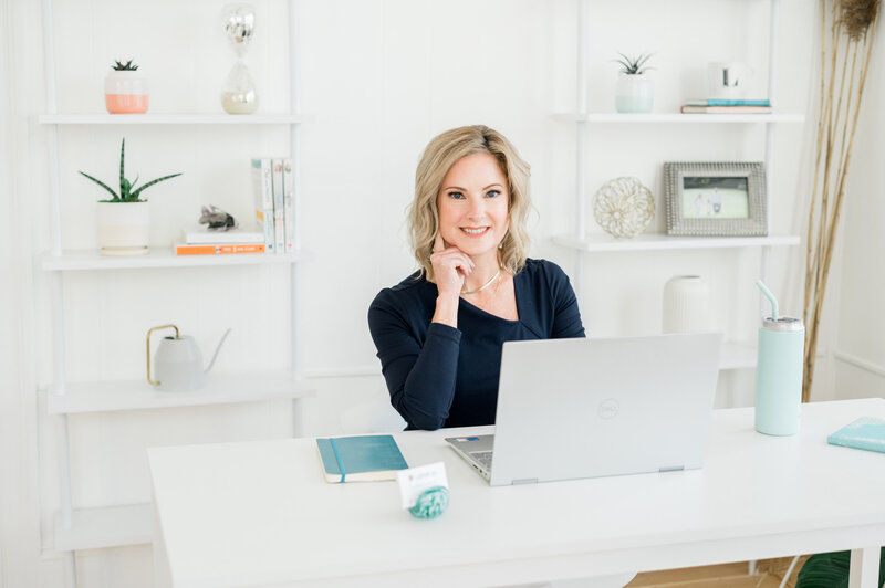 Julie Ladimer sitting at her desk with her laptop helping clients through her Wills in a Week program