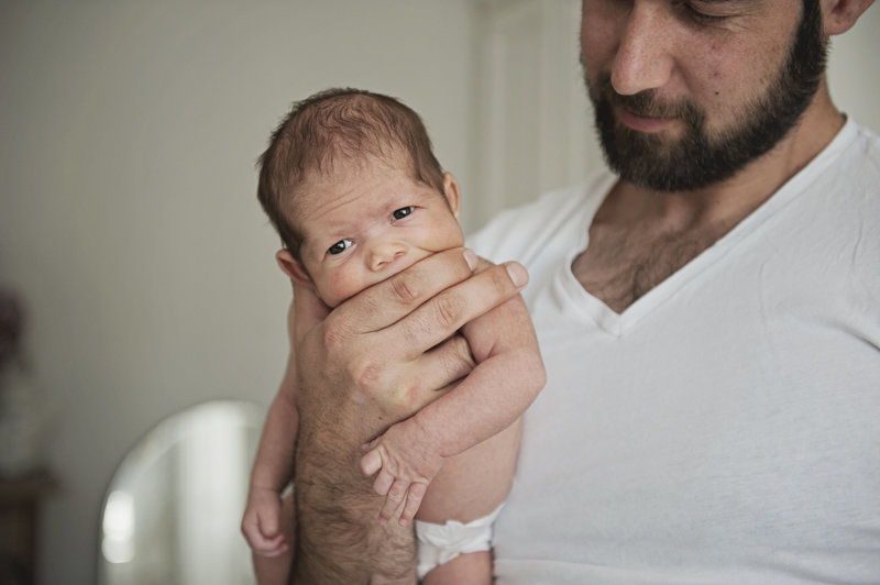 Newborn baby boy photographed in hand of father during photo shoot