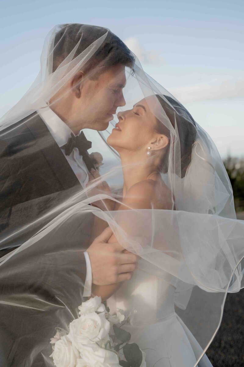 stunning portrait of couple under bride's veil during auckland wedding