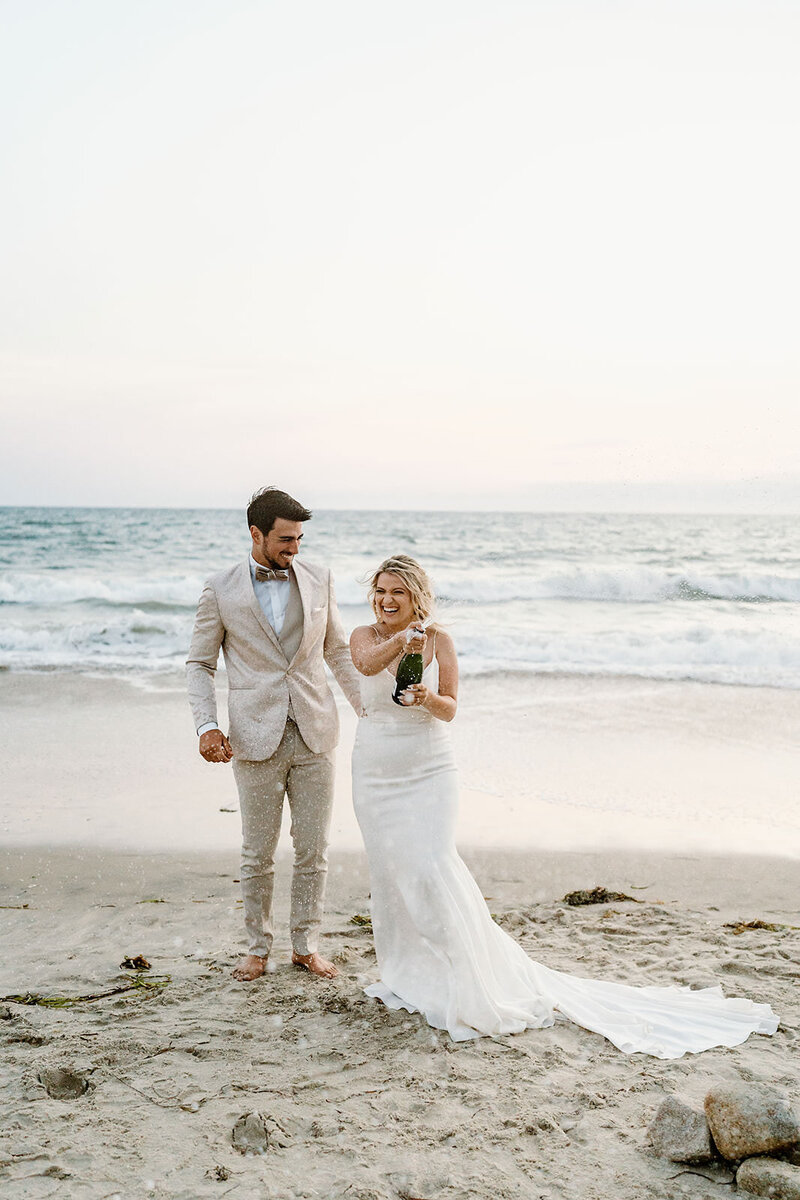 newlyweds pop champagne on beach