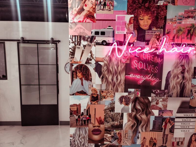 The hair extension wall at Moxie by KC is decorated in photos of our clients and team, adorned with a neon sign that says nice hair
