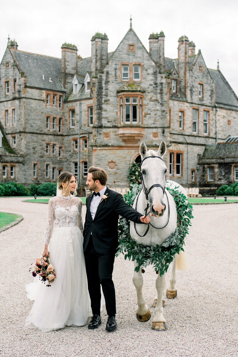 Tiffany Longeway captures a moment of enchantment at Castle Leslie, Ireland, where the elegance of a grand wedding is complemented by the majestic presence of a white horse, adding a fairy-tale touch to the Irish countryside setting.