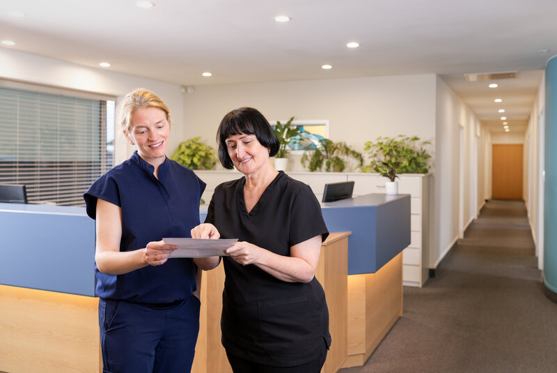 Dentist and dental assistant looking over paperwork in reception area