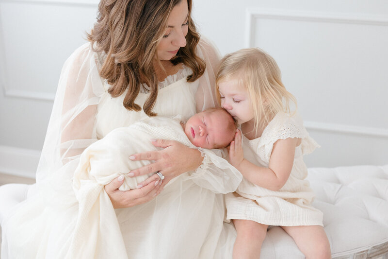 Mom and big sister loving on their newborn baby brother in a bright louisville KY studio