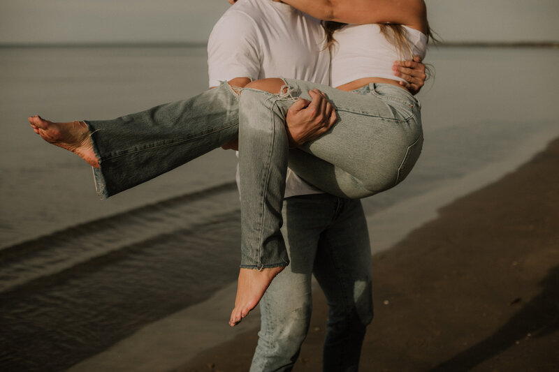 man carried woman in this arms for engagement session on the beach