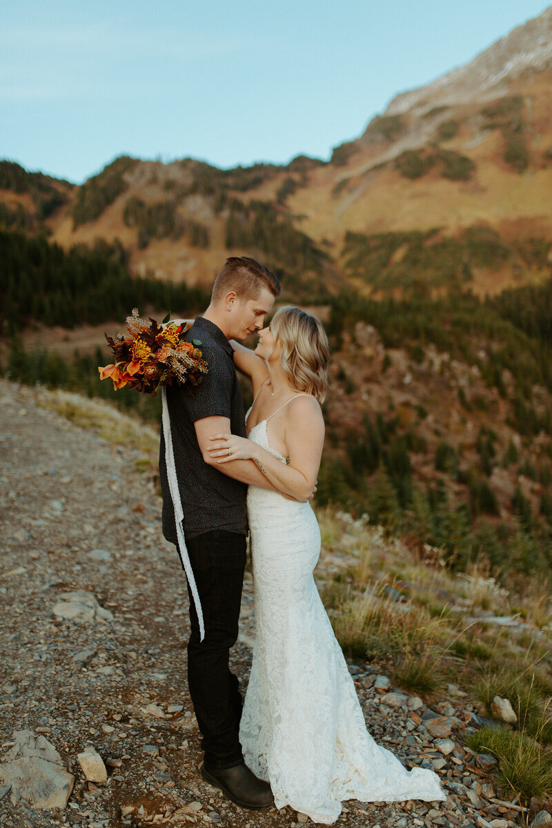 bride and groom holding each other on a mountain side