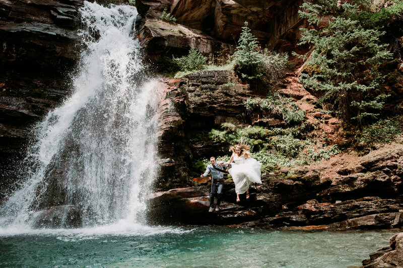Bride and groom jump into an alpine waterfall in Silverton, Colorado
