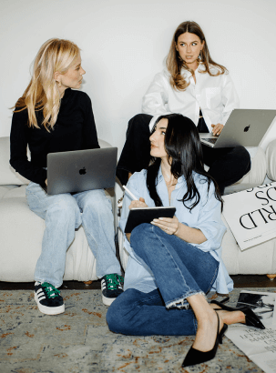 A team on laptops working together on a couch talking about a meeting 