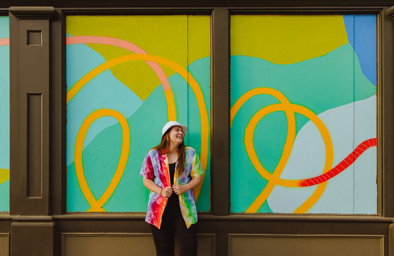 woman smiling and looking to the side in front of a colorful window