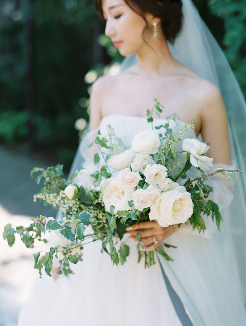 pretty asian bride in white strapless dress with veil and white bouquet