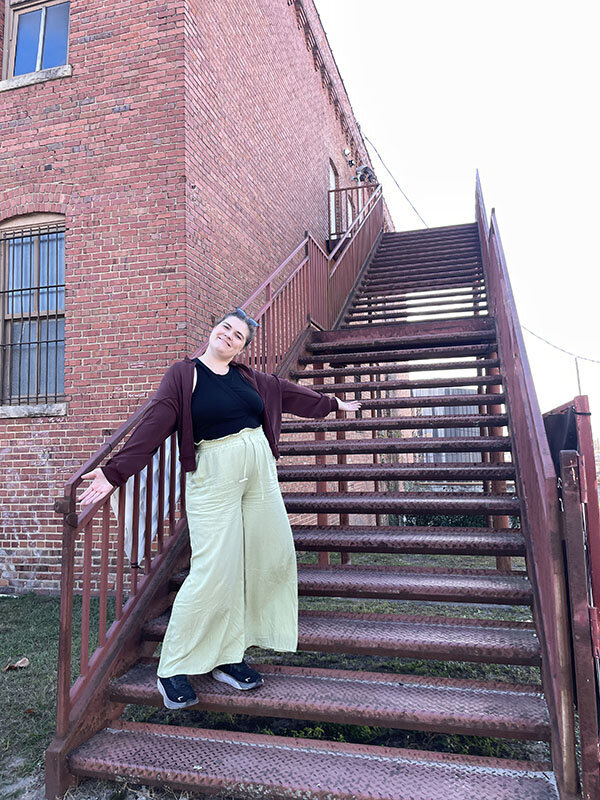 Becks, founder of Visuals by Becks, standing on outdoor staircase, combining travel inspiration with website design for entrepreneurs