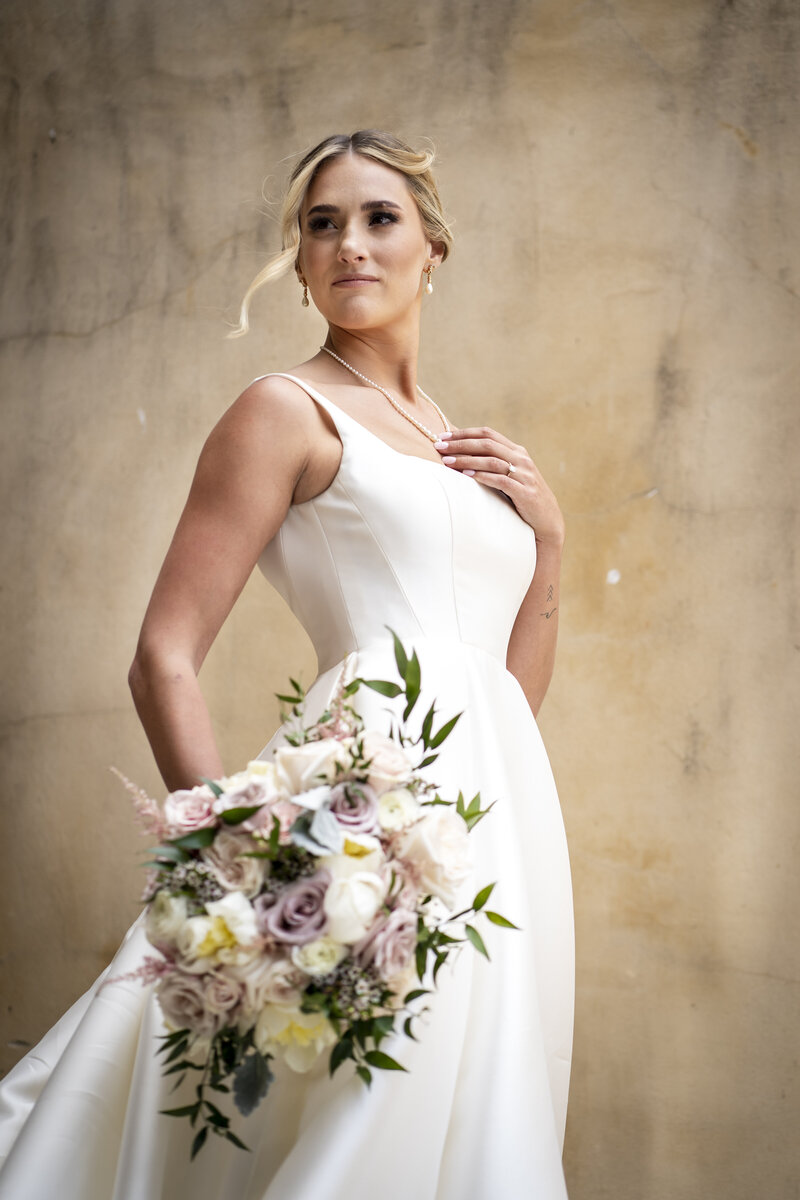 Bride standing in powerful pose holding bouquet