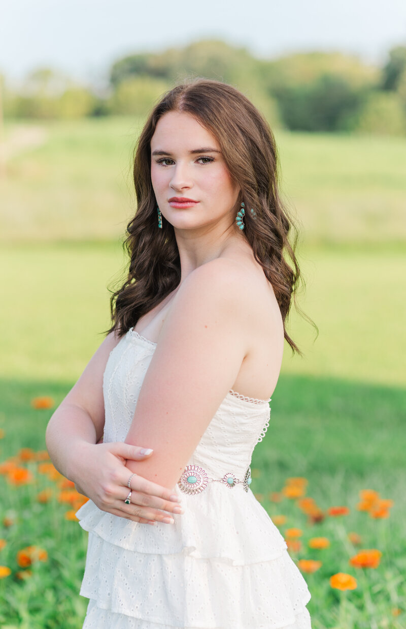 High school senior girl, standing in a field of wildflowers.
