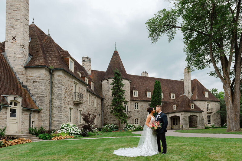 a full length portrait of a bride and groom outside Eaton Hall in Toronto.  Captured by Ottawa wedding photographer JEMMAN Photography