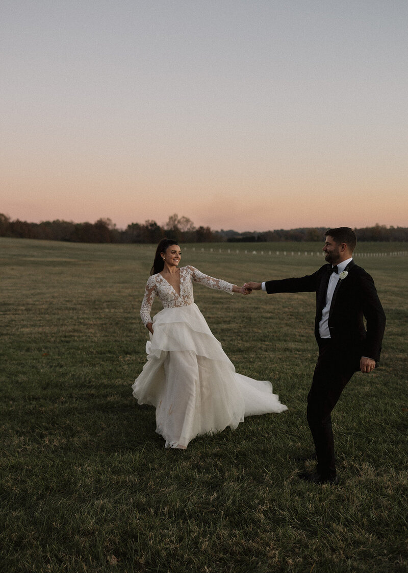 bride and groom walking through grass