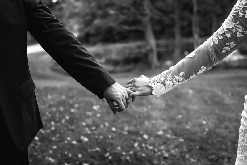 Bride and groom linking pinky fingers to show off wedding bands