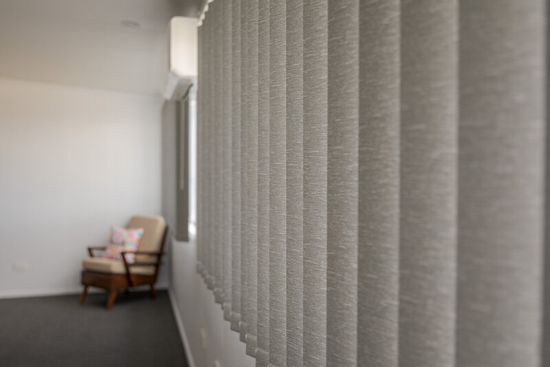 Modern bedroom featuring vertical blinds, offering privacy and light control in a sleek design.