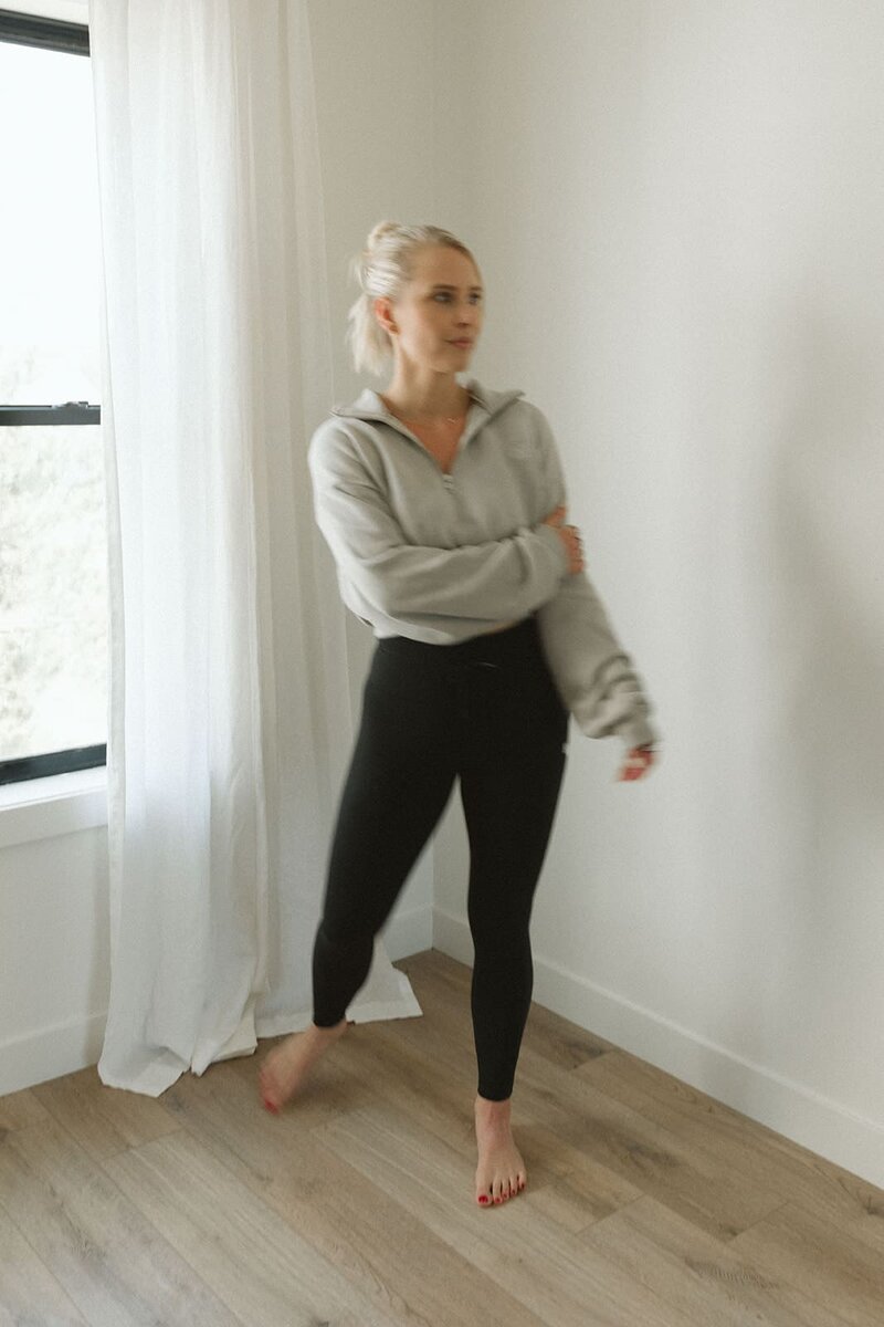 Candid photo of Lauren standing in soft light, mid-motion in a quiet, minimal space