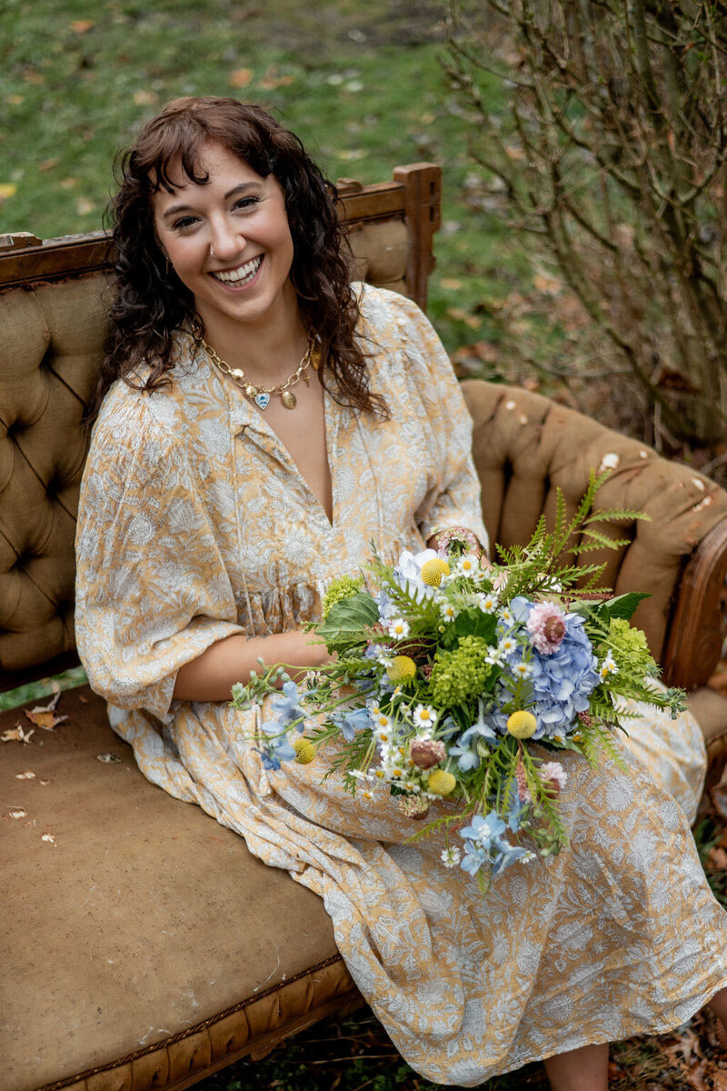 Pittsburgh wedding florist Heavenly Blooms sitting on a couch outdoors with a bouquet of flowers