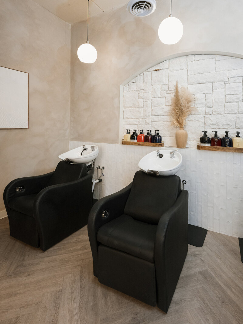 salon shampoo station with black chairs and white shampoo bowls