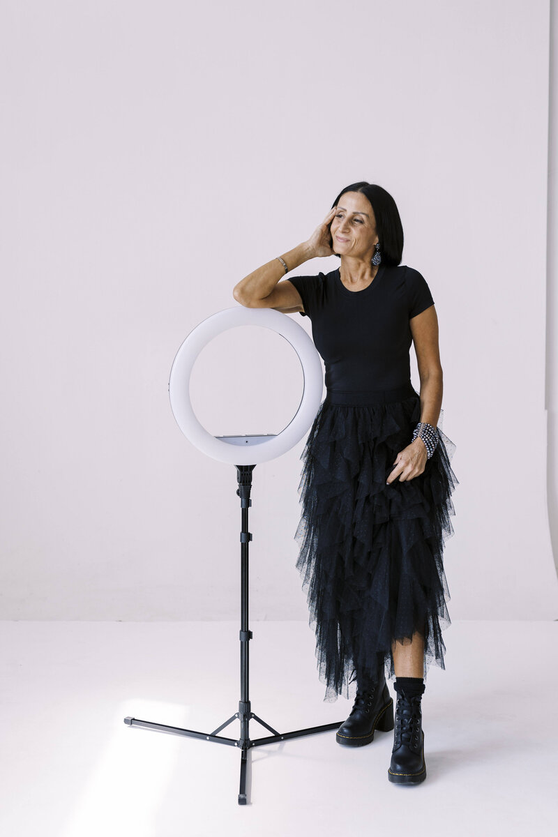 Cut out of Tarah wearing a black tool dress holding stage light