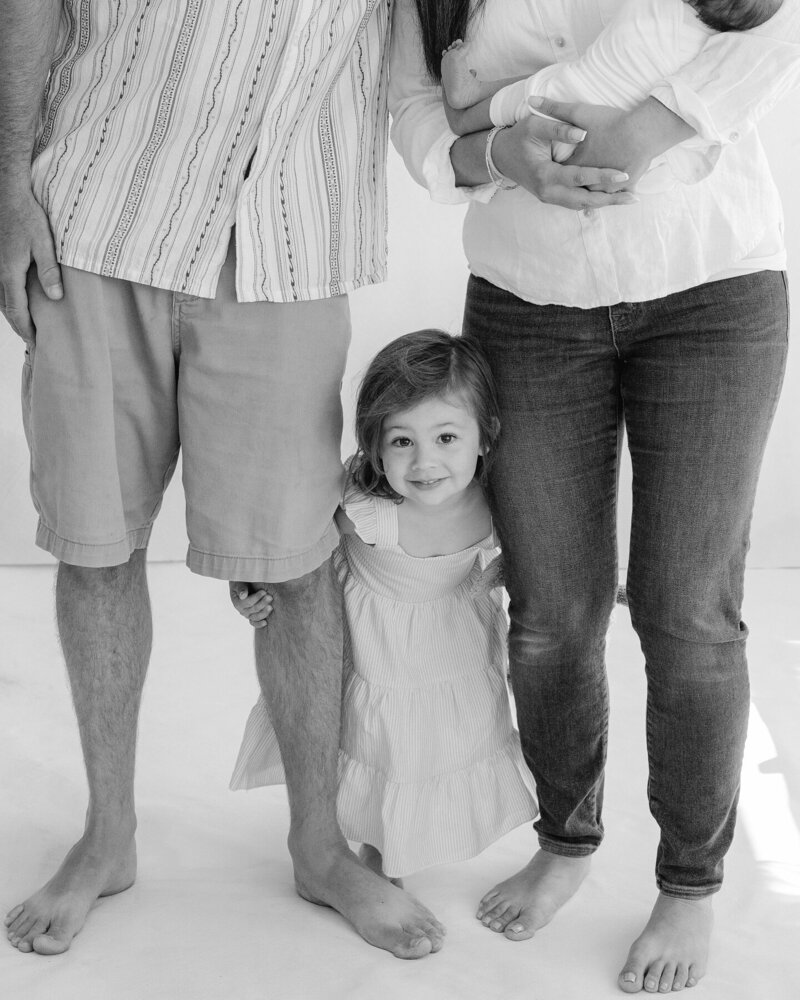 Candid black and white photo of a family sitting together at home, captured during an in-home lifestyle session in Northern California by Suzanne Karp from Little Palm Studio.