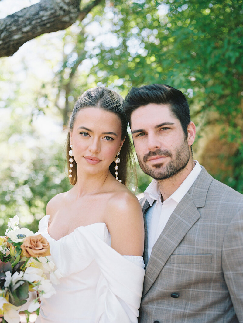Bride and groom smiling softly heads inclined together looking towards the camera