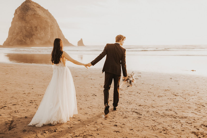 A bride and groom walking together holding hands during their Cannon Beach Elopement