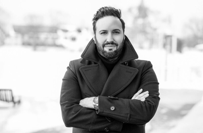 A Classic black-and-white portrait of a man with a long stylish jacket. 