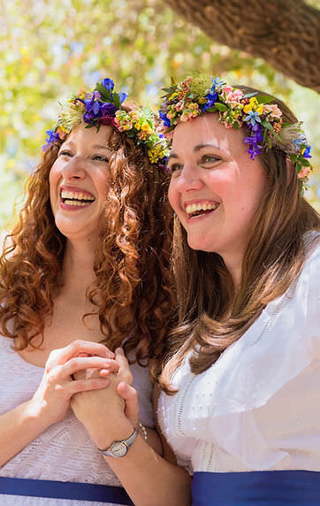 two women in flower crowns holding hands and smiling together