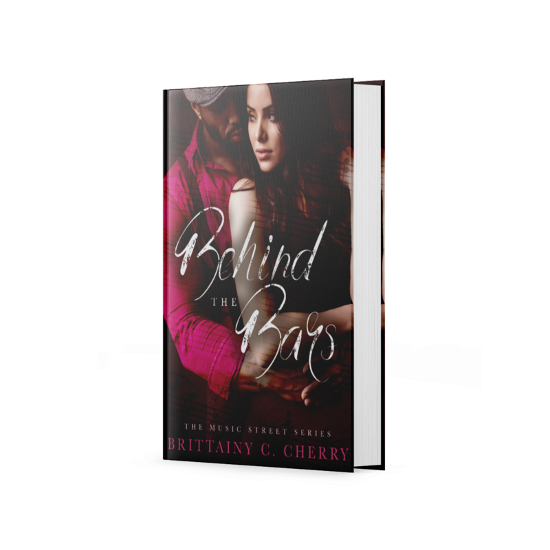 black man in a red shirt and red cap holding white brunette woman on the cover of behind the bars by romance author brittainy cherry