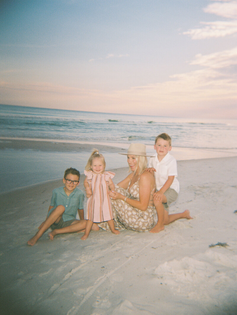 Flash film photo of mom and her three kids on the beach with the ocean in the background