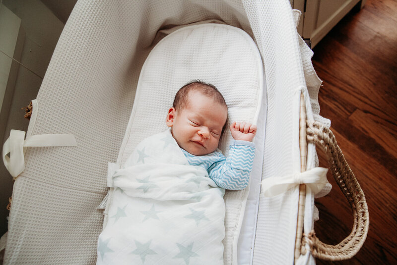 Sleeping newborn boy in moses basket