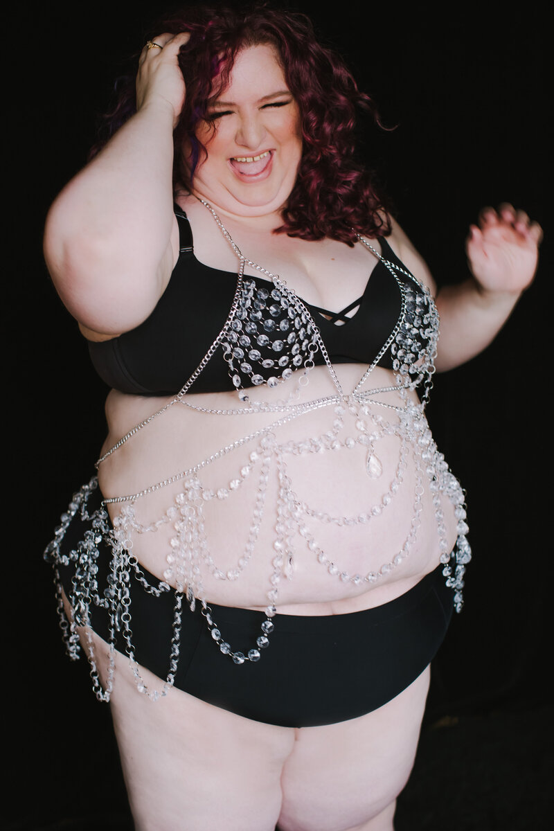 Plus size photographer in bliack lingerie with crystal body chain having fun and laughing in Minneapolis