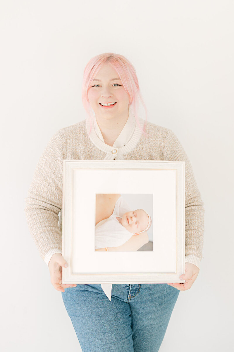 central Indiana family photographer Brittney Lear holds camera while siting on the floor and smiling