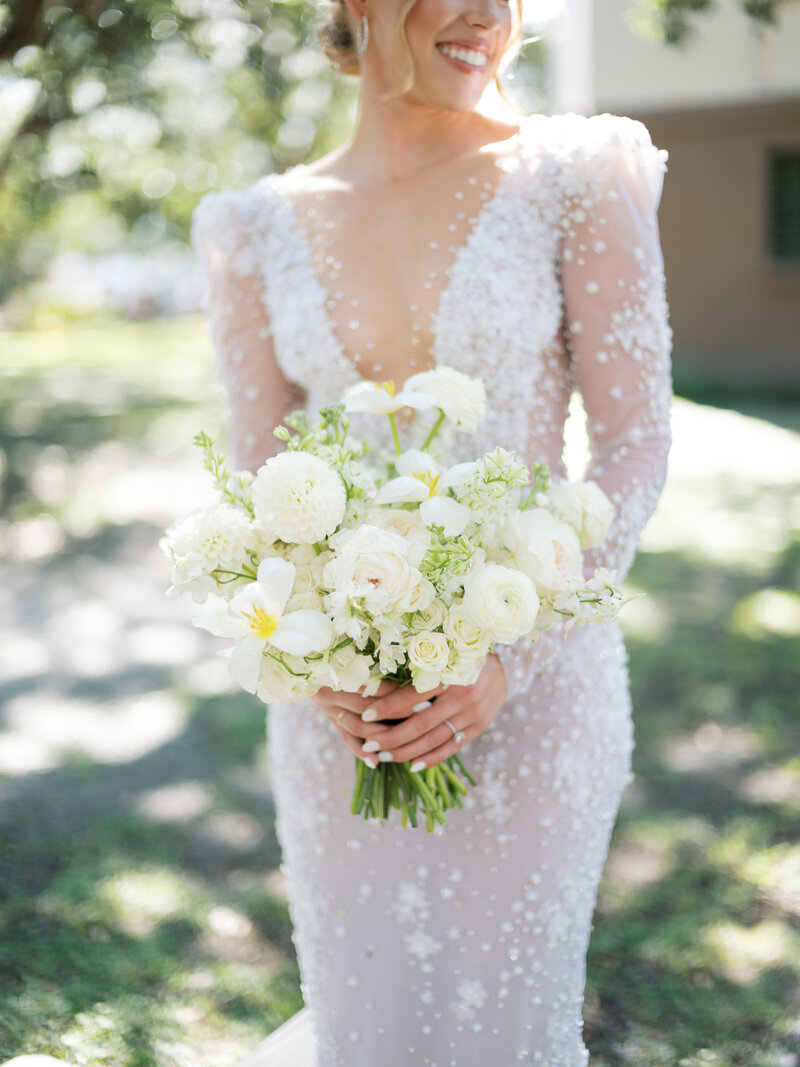 bride in beaded lace gown holding bouquet of white flowers