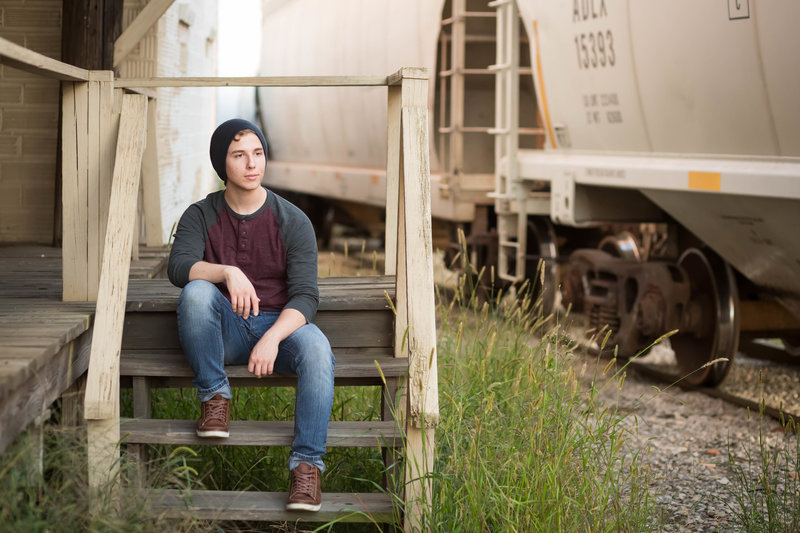 high school guy sitting on old rustic steps beside a train yard, photographed in Wooster Ohio, photographed by Jamie Lynette Photography