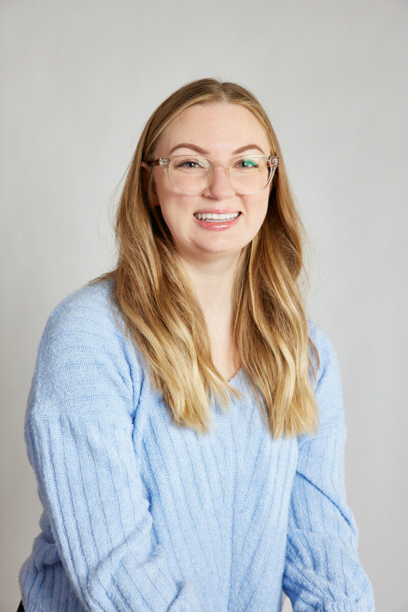 woman professional headshot with glasses and blue sweater