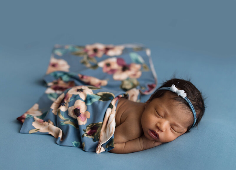 Infant girl on blue backdrop and floral wrap