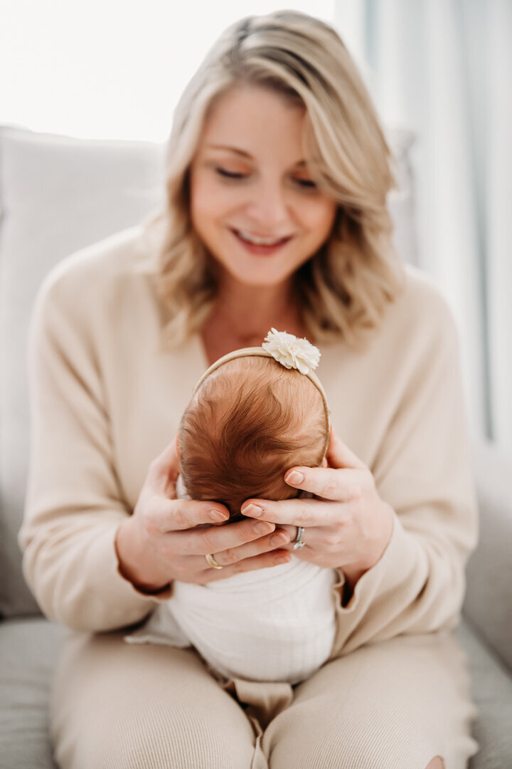 Newborn Photographer, a mother holds her newborn baby in her arms at home